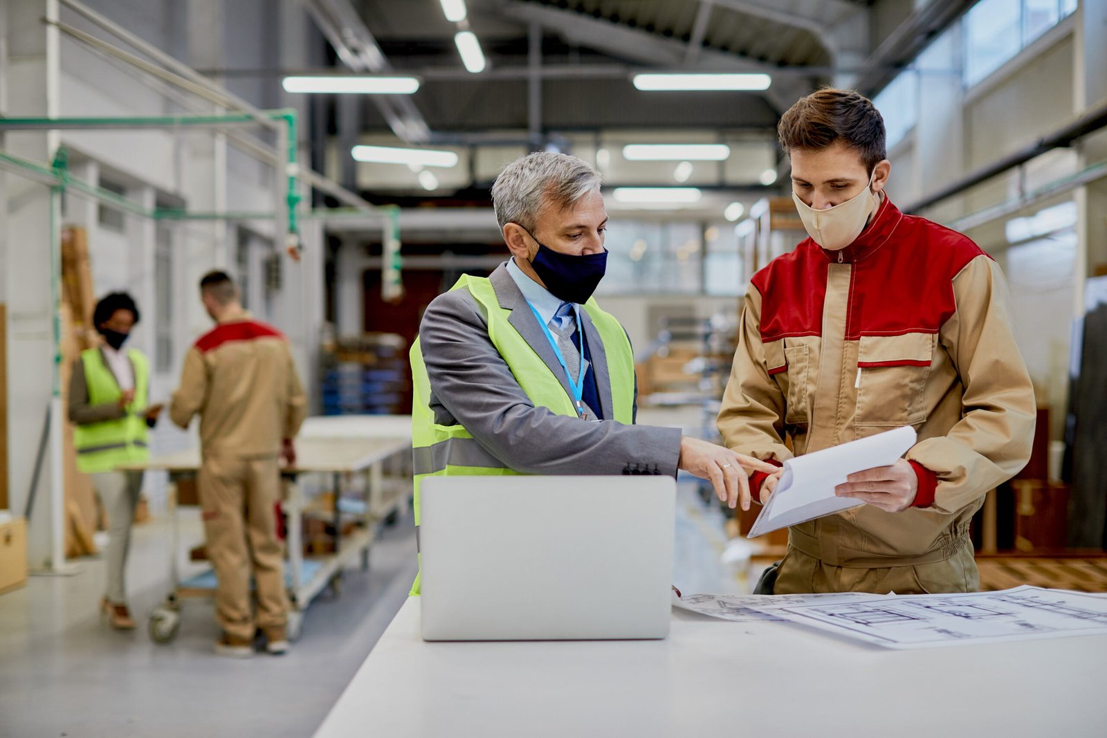 mid adult engineer male worker wearing face masks while examining paperwork woodworking factory scaled